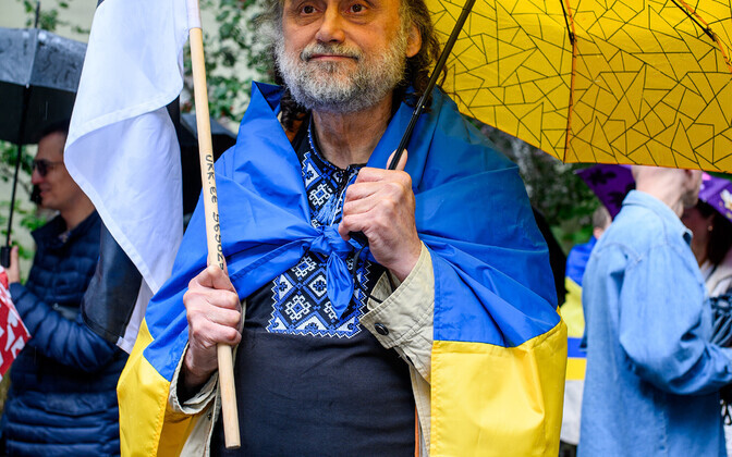 A woman holds a blue and yellow Ukrainian flag embroided with the word 