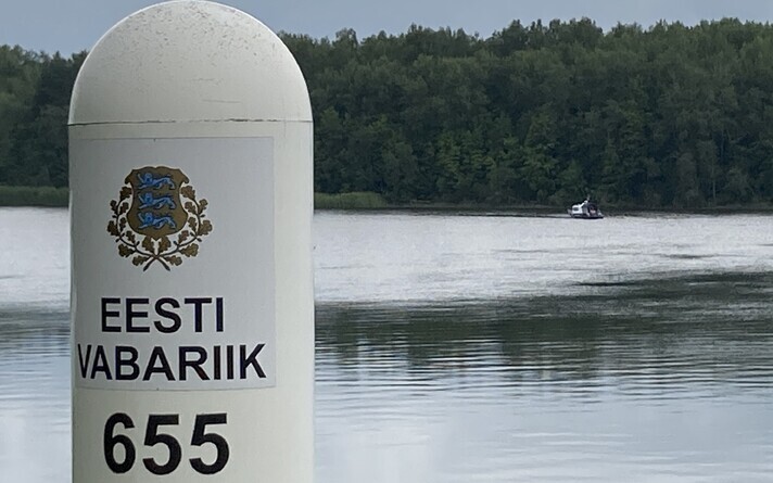 A border post along the Narva River with a Russian border guard vessel in the background.